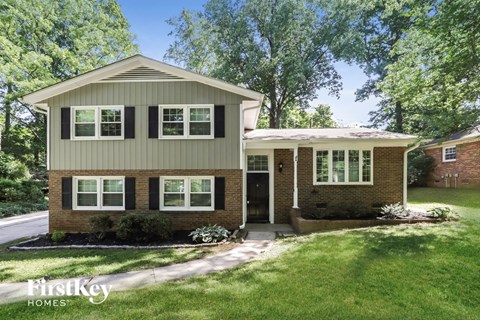 a home with a green roof and a lawn and trees