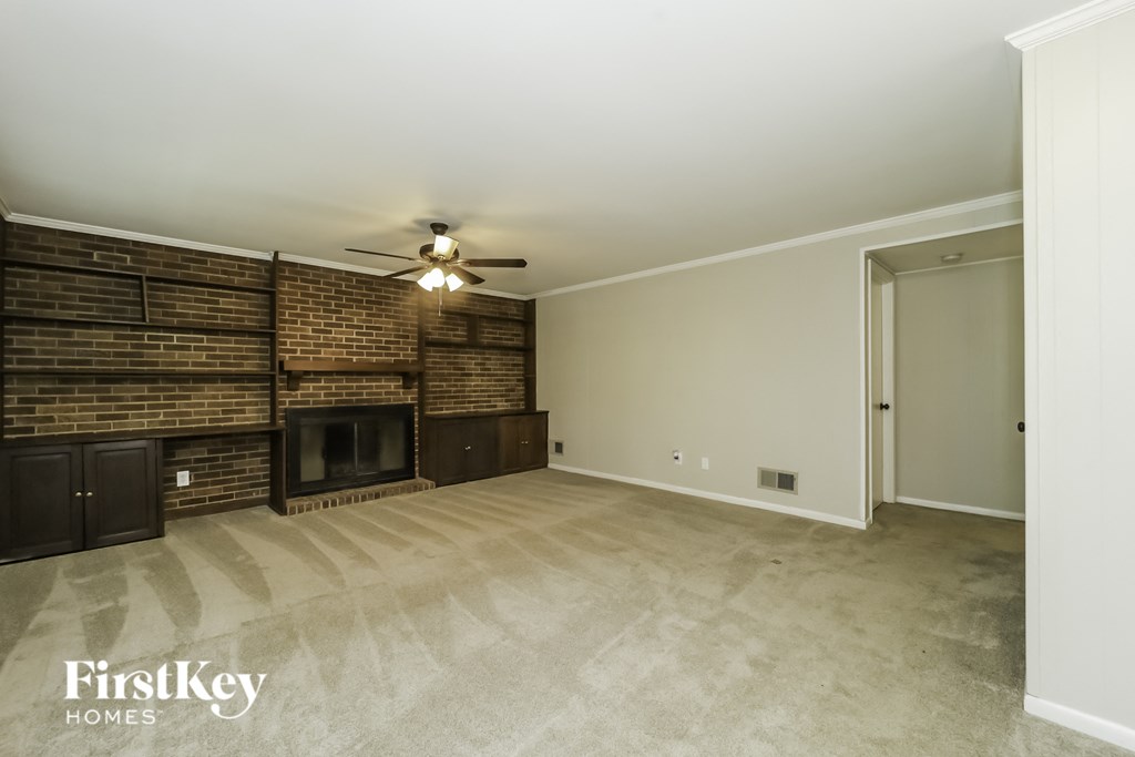 a living room with a brick fireplace and a ceiling fan