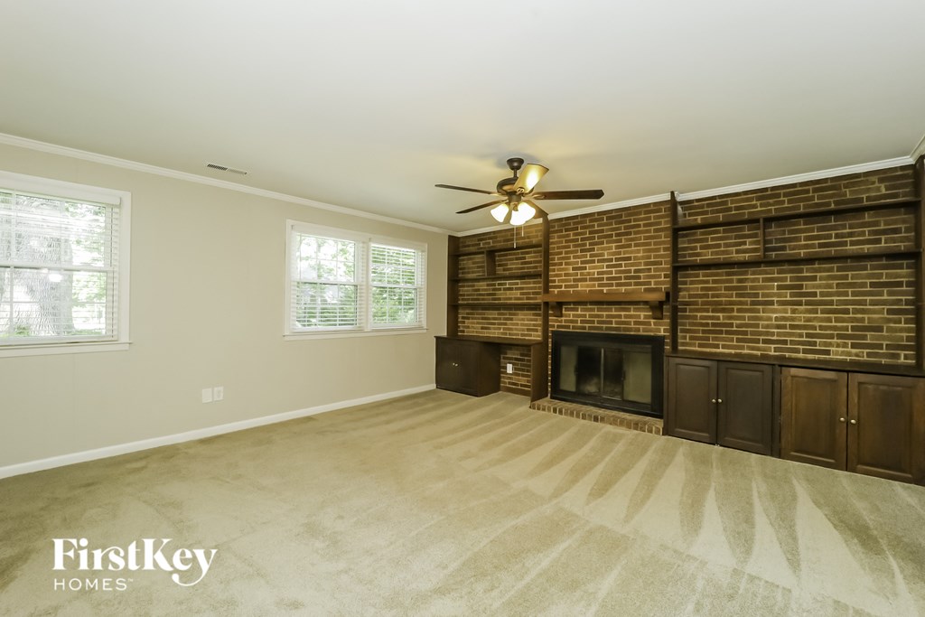 a living room with a brick fireplace and a ceiling fan
