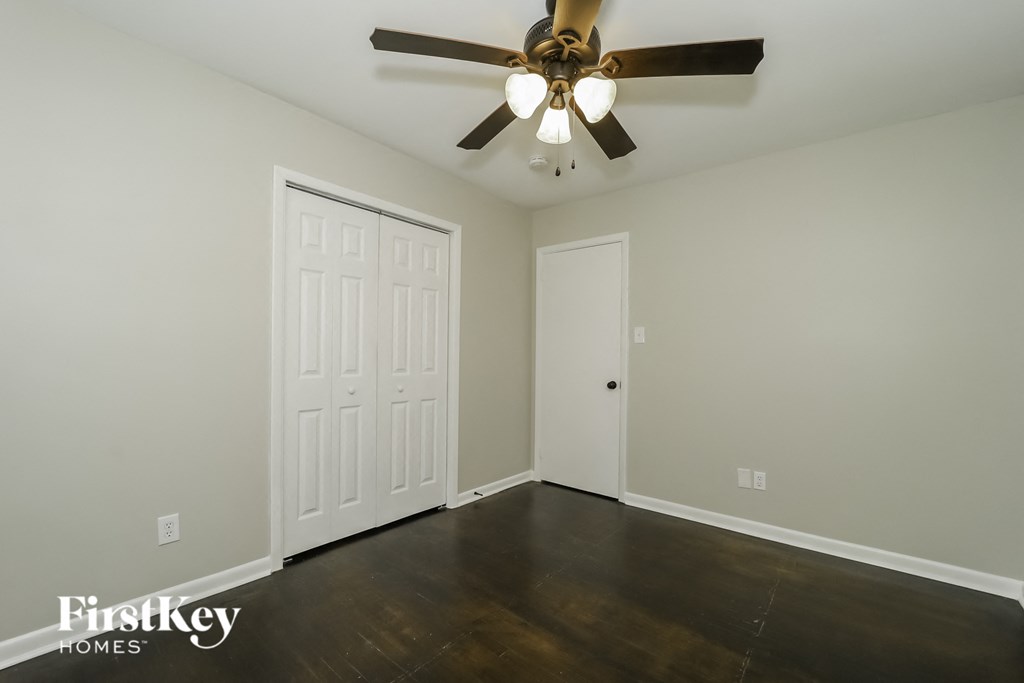 a bedroom with wood floors and a ceiling fan