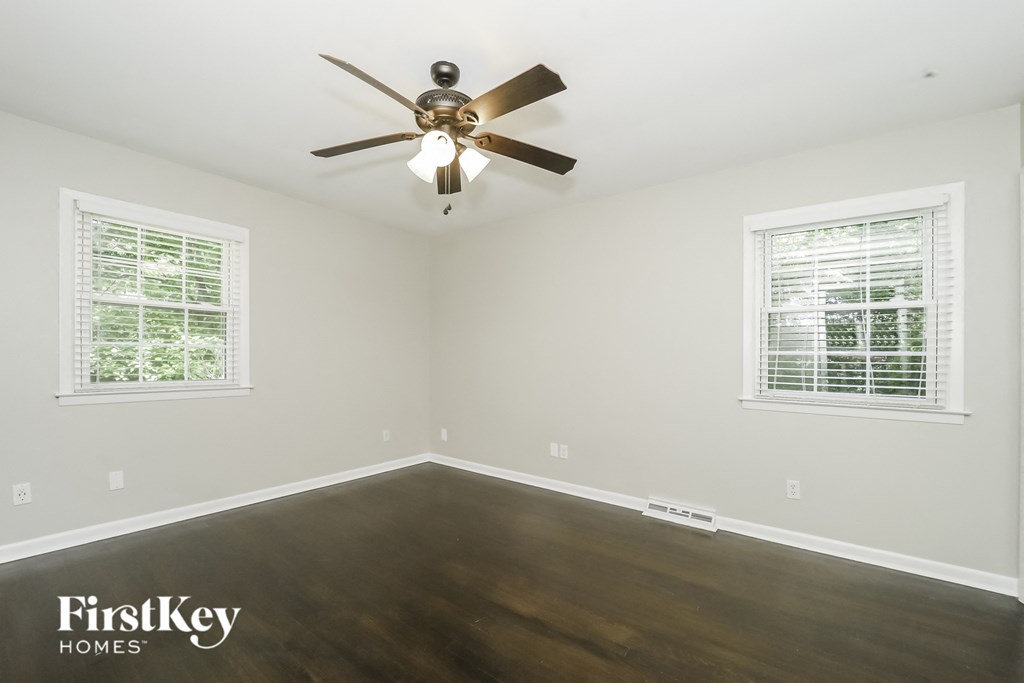 a bedroom with wood floors and a ceiling fan