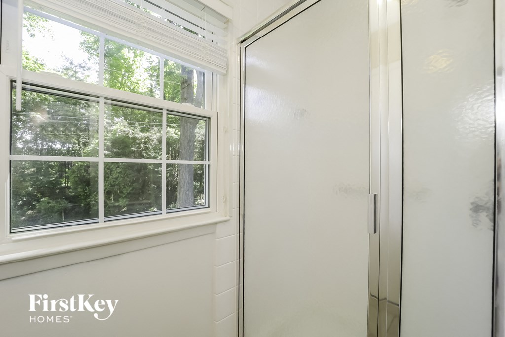 a glass shower door with a window in a white bathroom