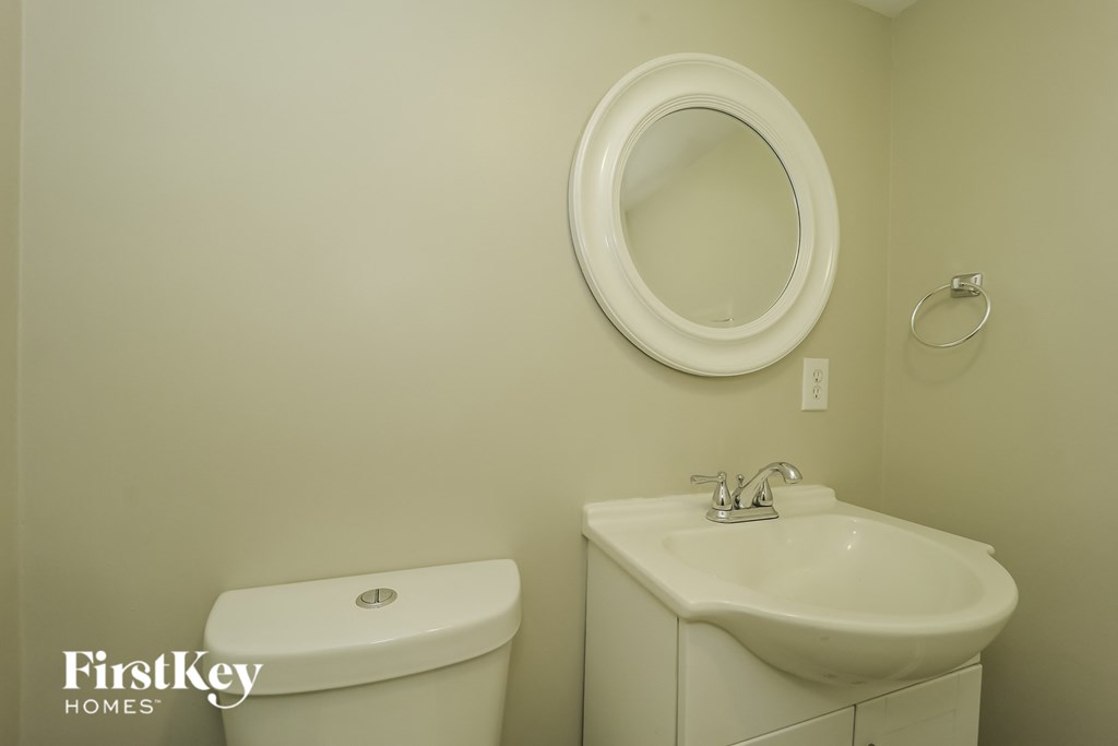 a white bathroom with a white toilet and a sink and a mirror