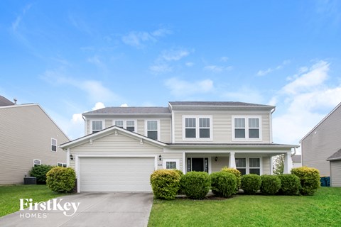 a white house with a garage door and a lawn