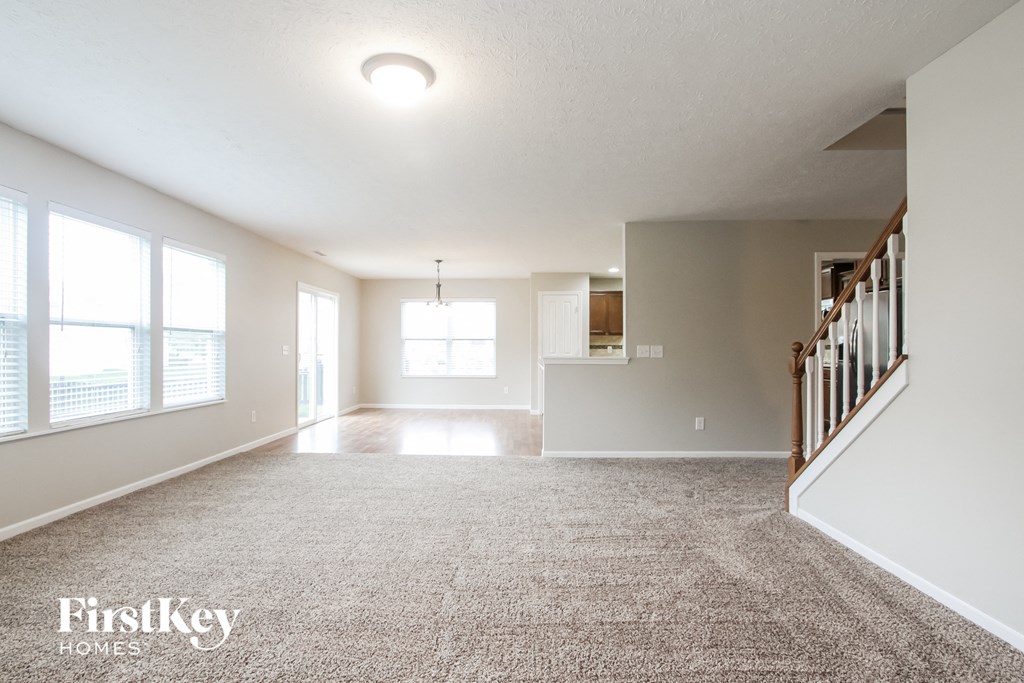 an empty living room with a staircase and a large window
