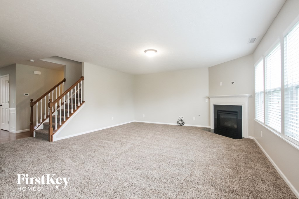 an empty living room with a fireplace and a staircase
