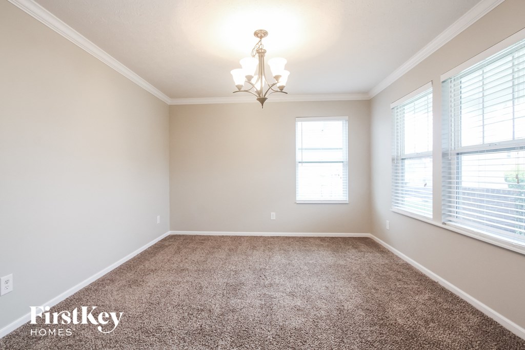 a carpeted room with two windows and a chandelier