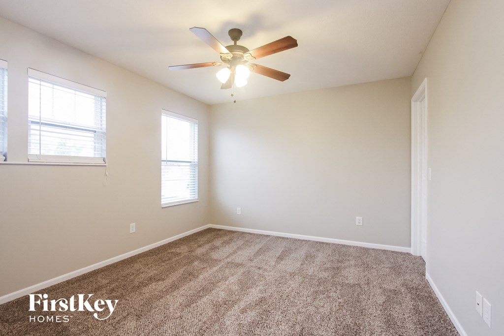 the spacious living room with carpet and ceiling fan