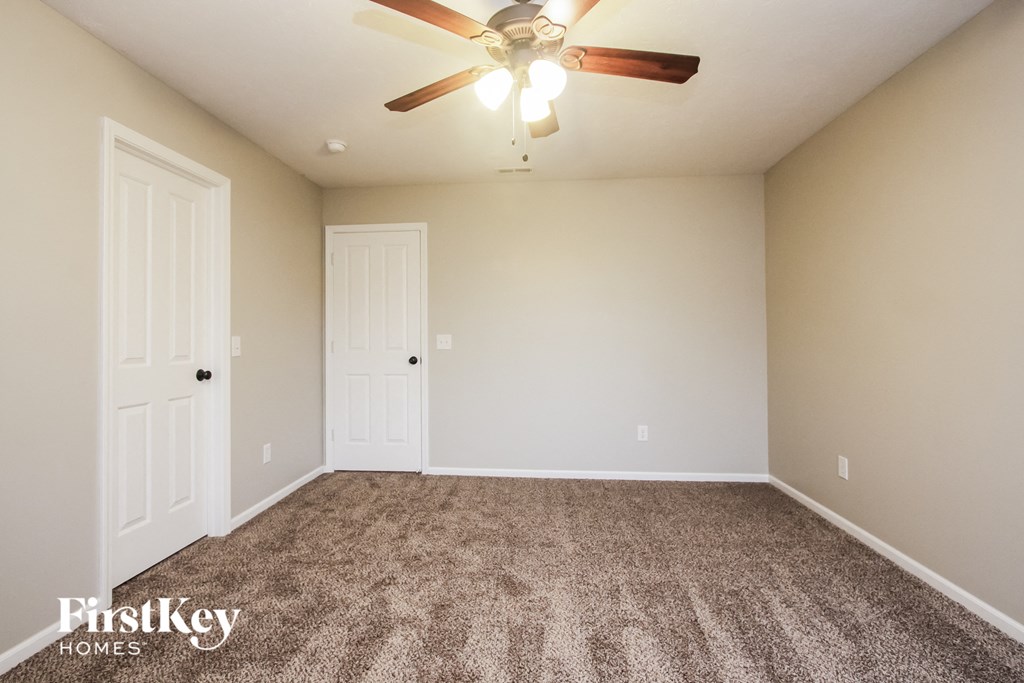the spacious living room with carpeting and a ceiling fan