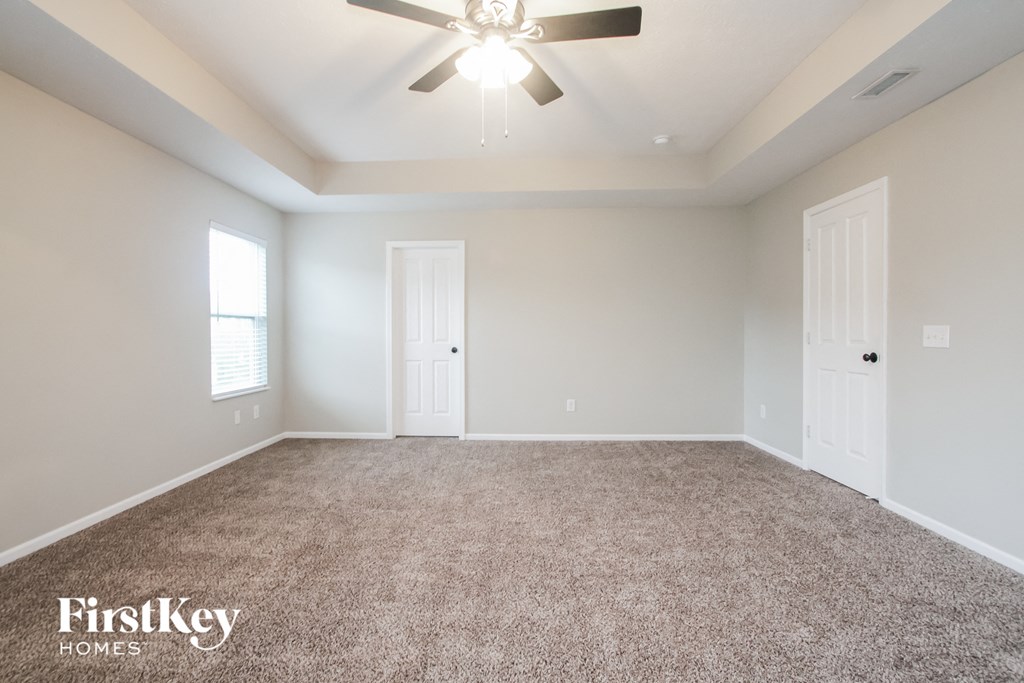 the spacious living room with carpeting and a ceiling fan
