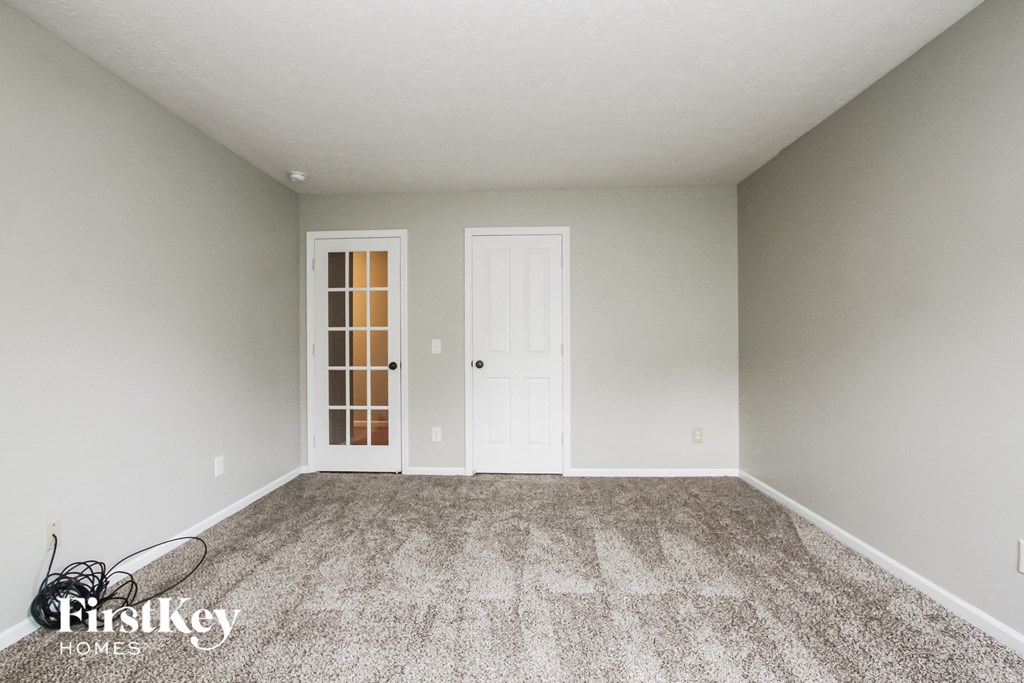 an empty living room with carpet and a white door