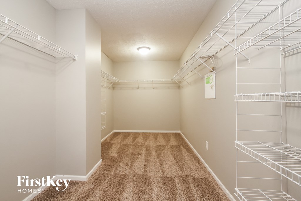 a spacious closet with white shelves and a carpeted floor