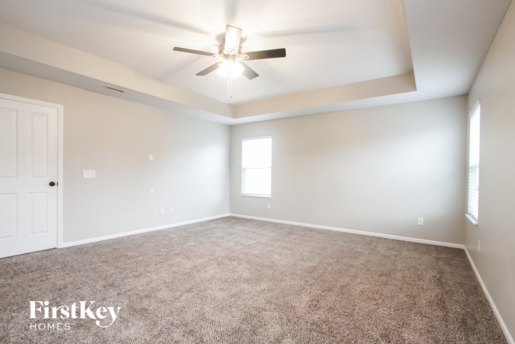 the spacious living room with carpeting and a ceiling fan