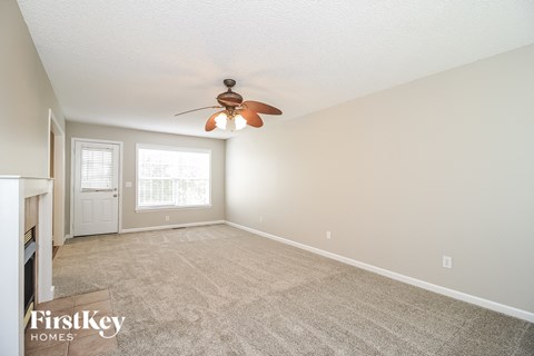 A spacious room with a ceiling fan and carpeted floor.