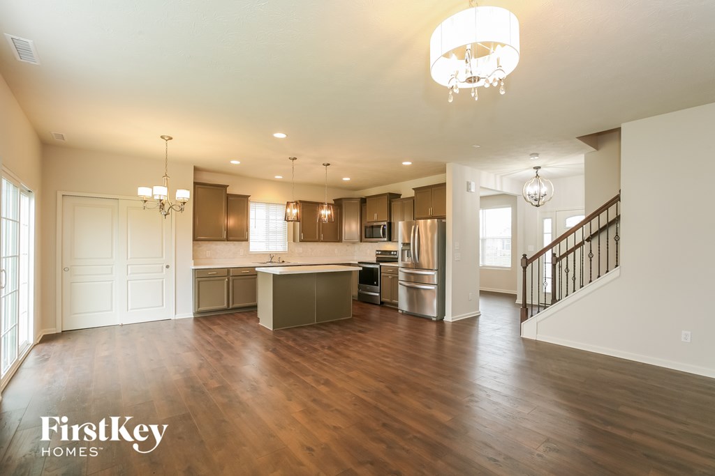 an open kitchen and living room with wood flooring and a staircase