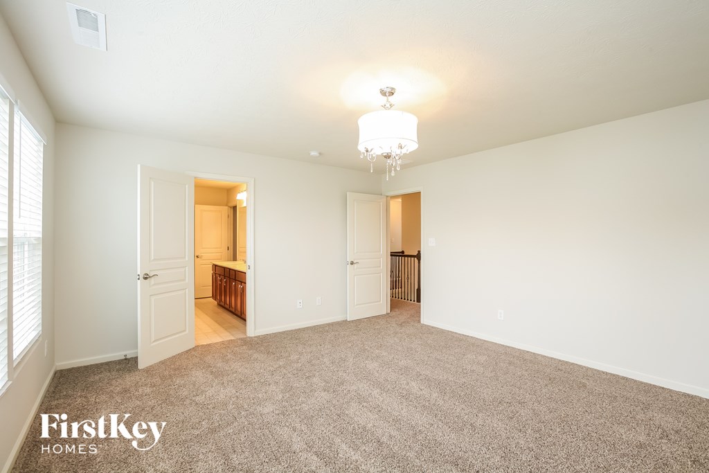 a spacious living room with carpet and a door to the kitchen