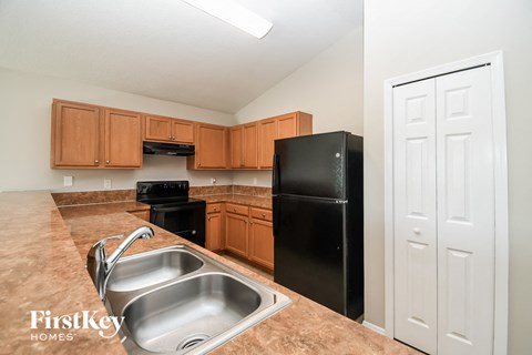 A kitchen with a black refrigerator and brown cabinets.