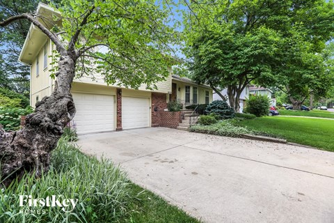 a house with a driveway and a tree in front of it