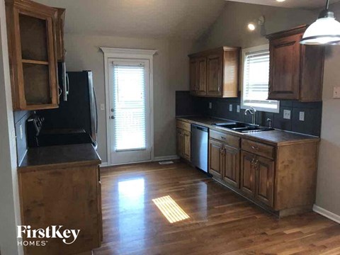 A kitchen with wooden cabinets and a black fridge.