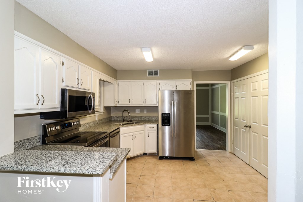 a kitchen with white cabinets and a stainless steel refrigerator