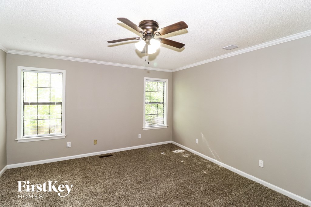 a empty room with a ceiling fan and a carpet