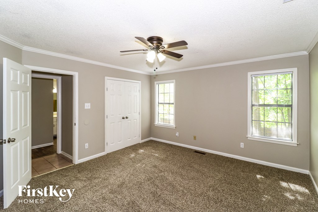 an empty living room with a ceiling fan and a door