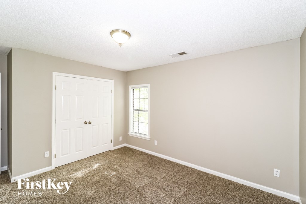 the spacious living room with carpeted flooring and a white door