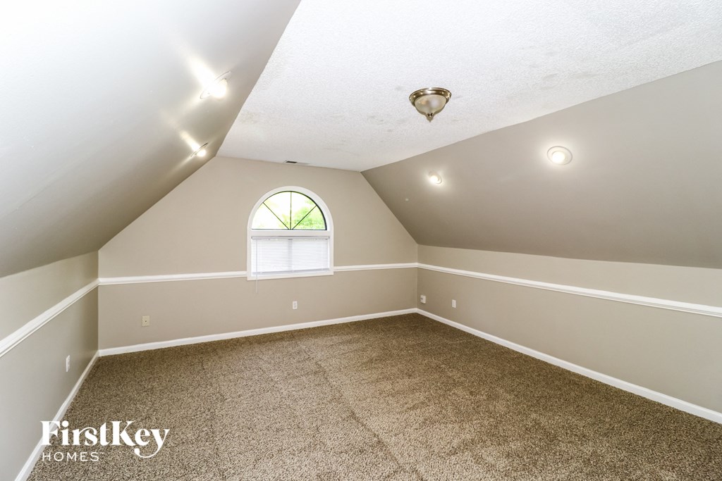 the bonus room has a vaulted ceiling and a window