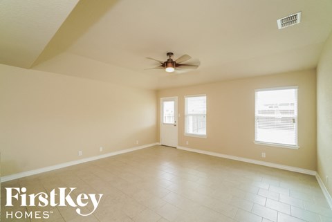 A spacious room with a ceiling fan and two windows.