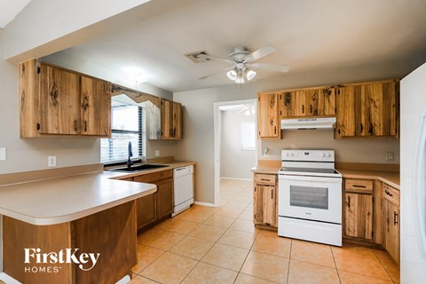 A kitchen with wooden cabinets and a white stove top oven.