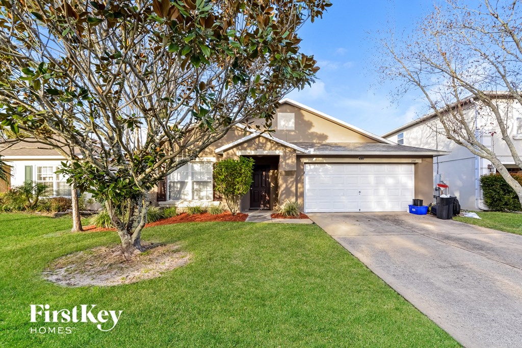 a home with a lawn and a tree in front of it