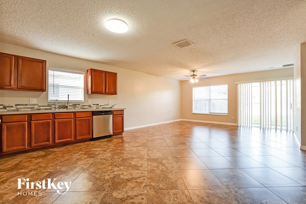 an empty living room with a kitchen and a sliding glass door