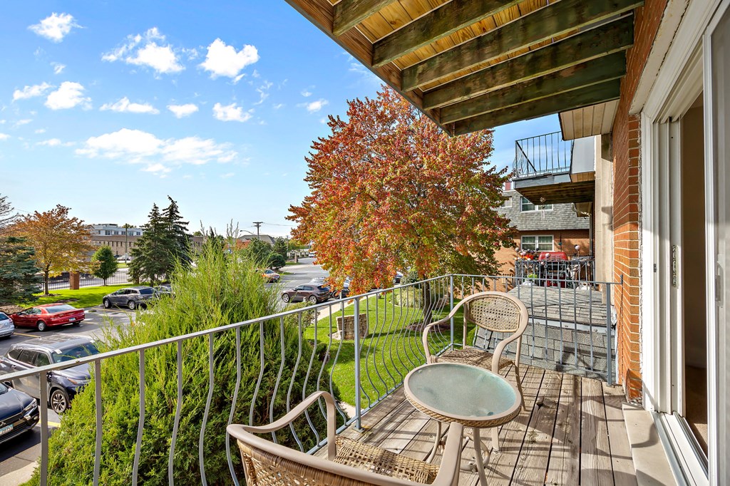 a balcony with a table and chairs and a view of a parking lot
