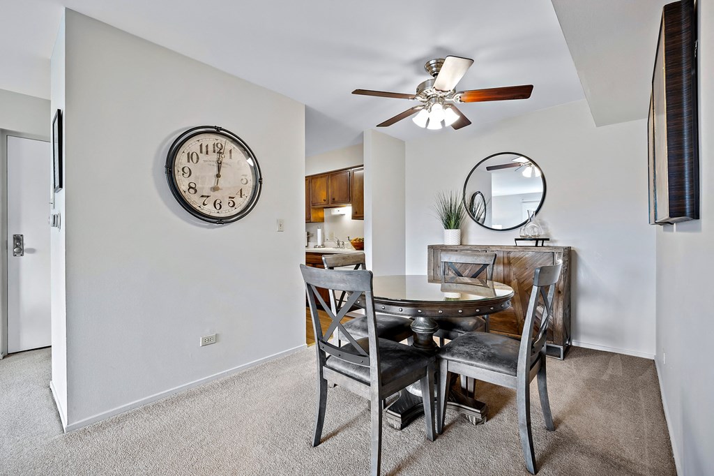 a dining room with a table and chairs and a clock on the wall