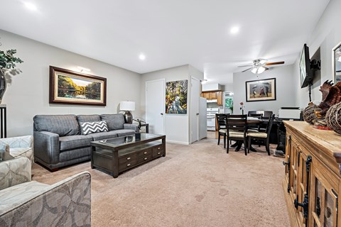 A living room with a grey couch and a painting on the wall.
