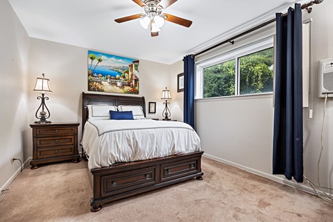 A bedroom with a bed, nightstands, and a ceiling fan.