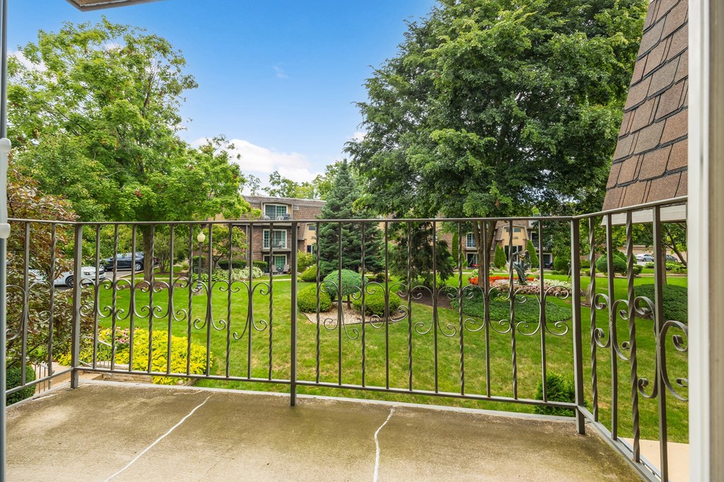 a balcony with a view of a garden and a fence