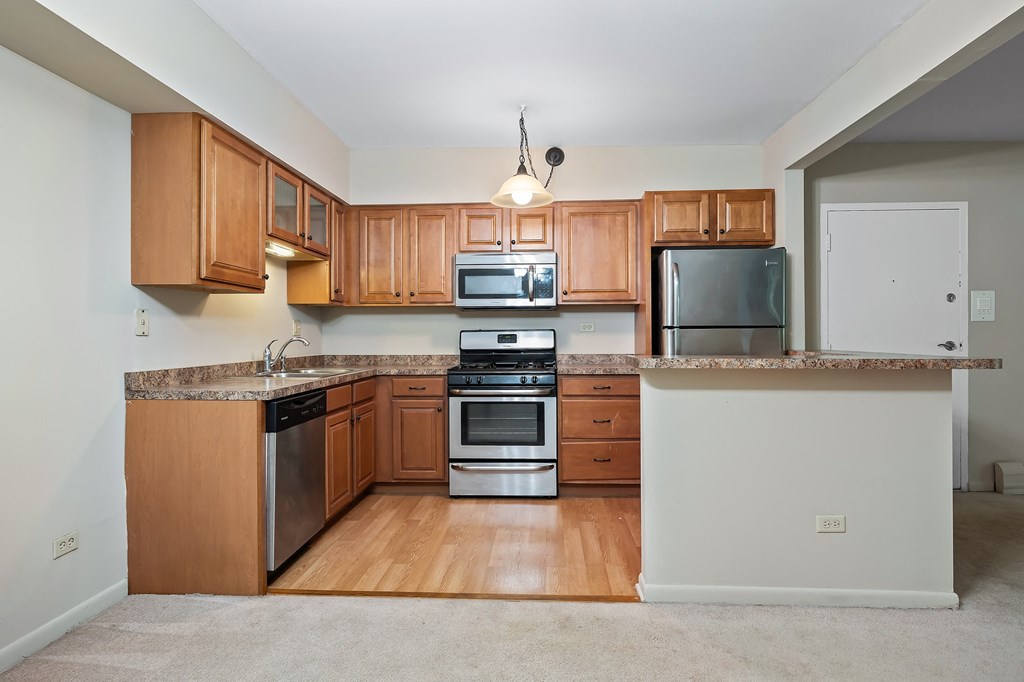 an empty kitchen with wooden cabinets and stainless steel appliances