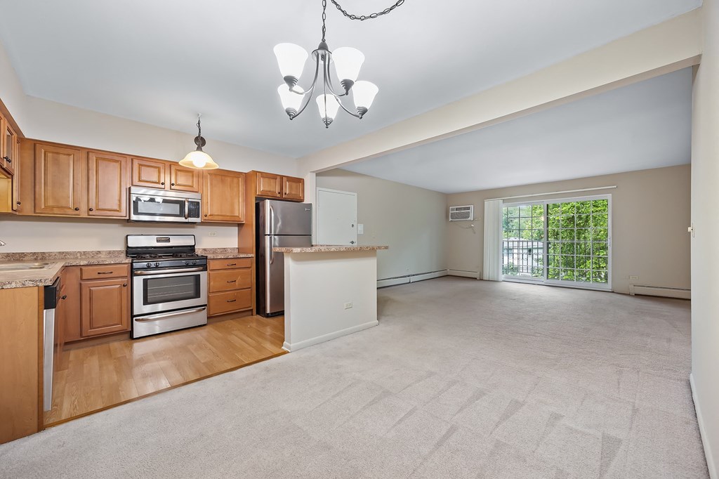 an empty kitchen and living room with wood cabinets
