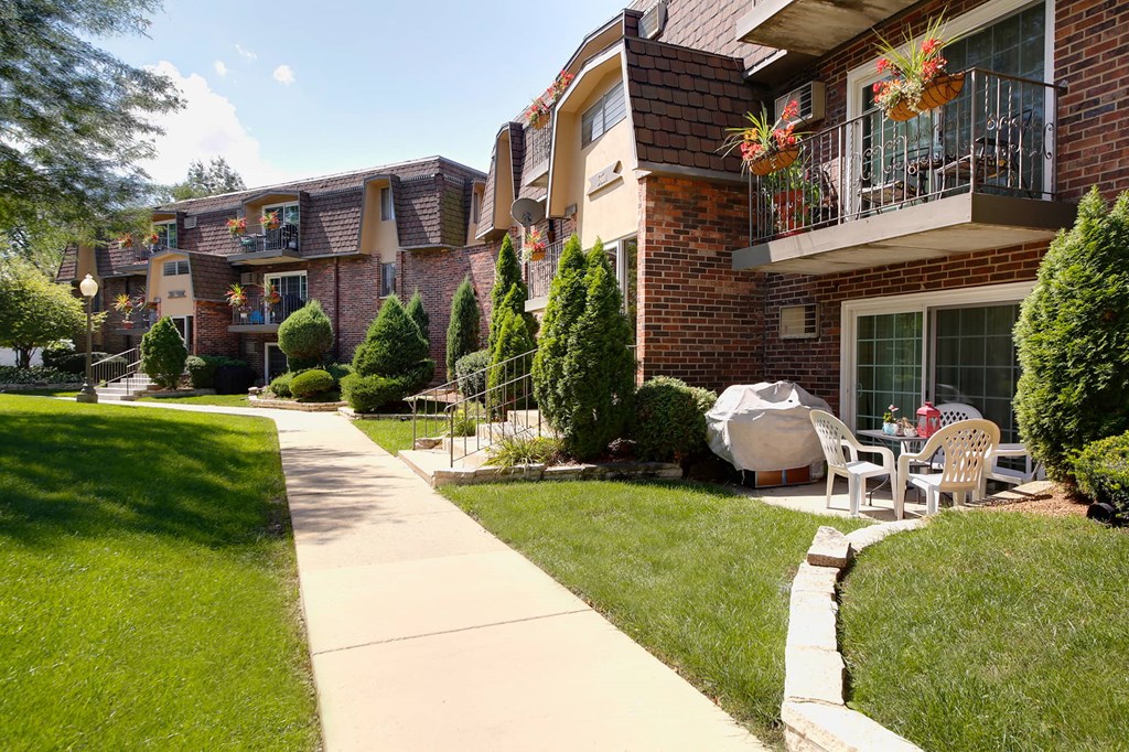 a sidewalk in front of a building with patio furniture