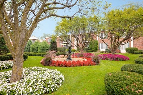 a garden with flowers and a fountain in front of a building