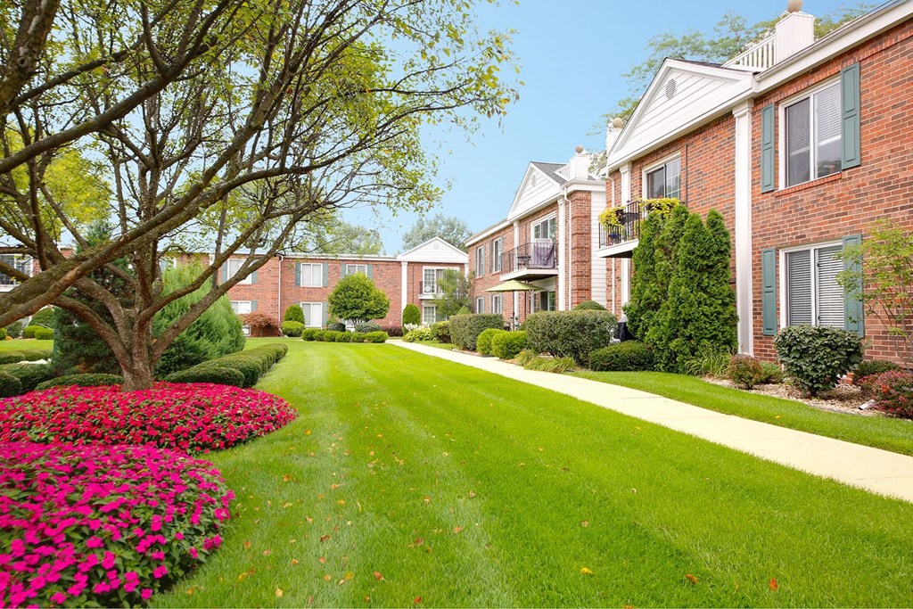 a lush green lawn in front of a brick apartment building