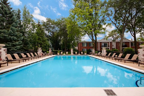 A large swimming pool surrounded by trees and lounge chairs.