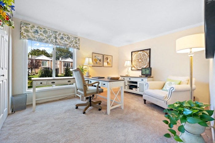 a living room with a desk and a window