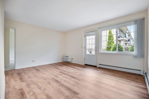 A room with a window overlooking a tree and a building.