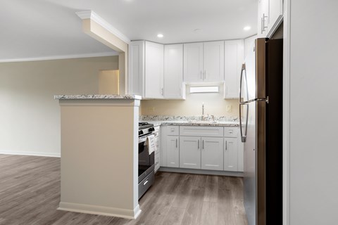 A kitchen with white cabinets and a refrigerator.