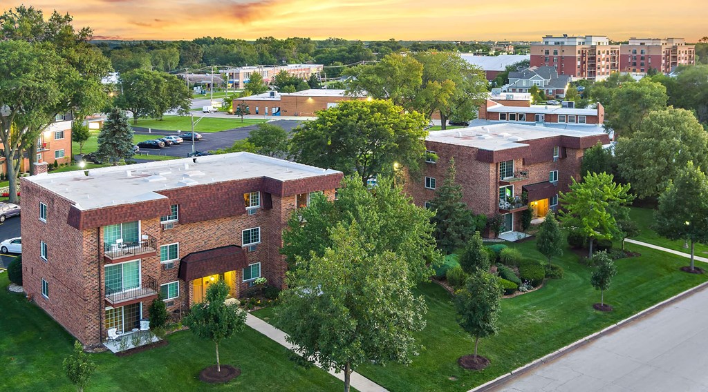 an aerial view of a building with trees and a sunset in the background