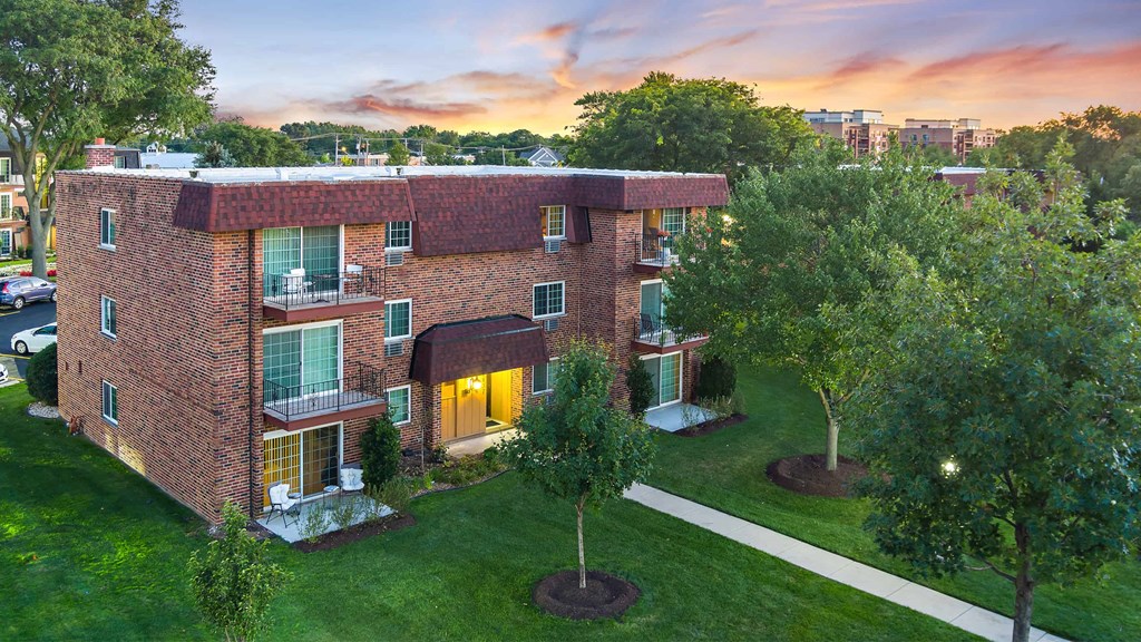 an aerial view of a brick apartment building with a sunset in the background