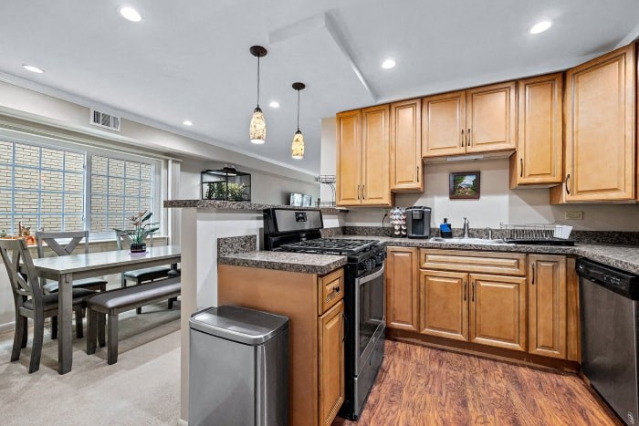 a kitchen with wooden cabinets and black appliances and a table