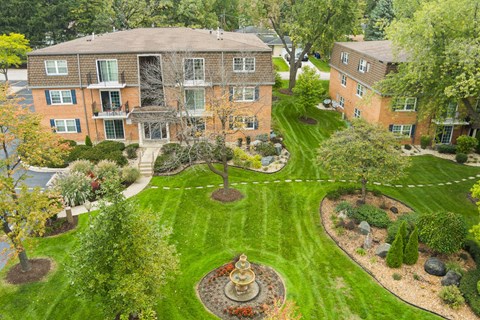A large building with a fountain in the front yard.